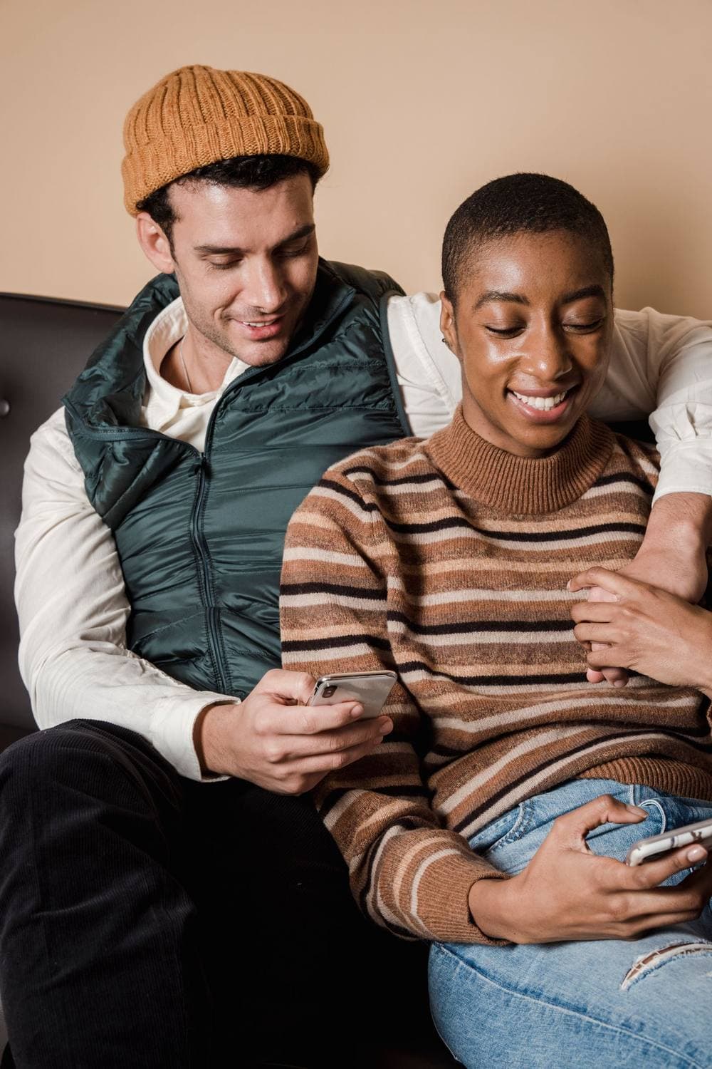 Pareja sonriente en el sofá, revisando el celular juntos