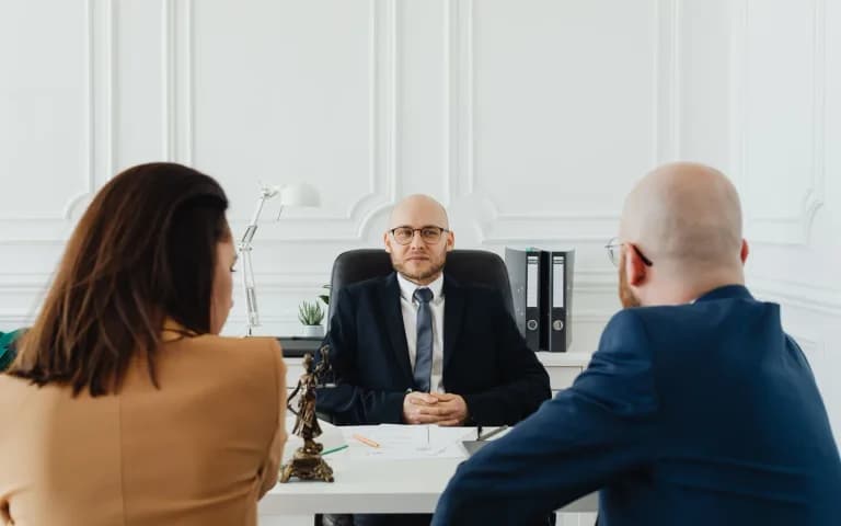 A couple consulting a lawyer together in a formal office setting.